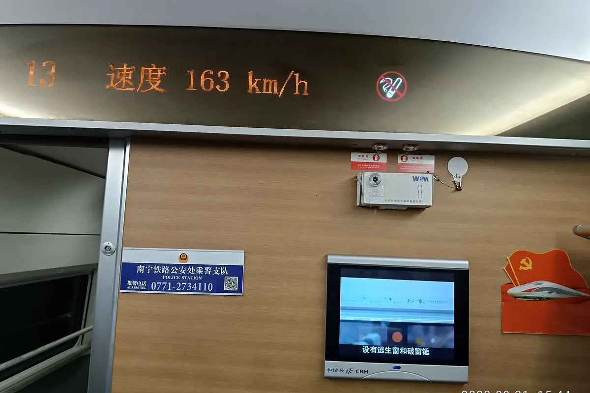 Train carriage display showing a speed of 163 km/h above an onboard screen