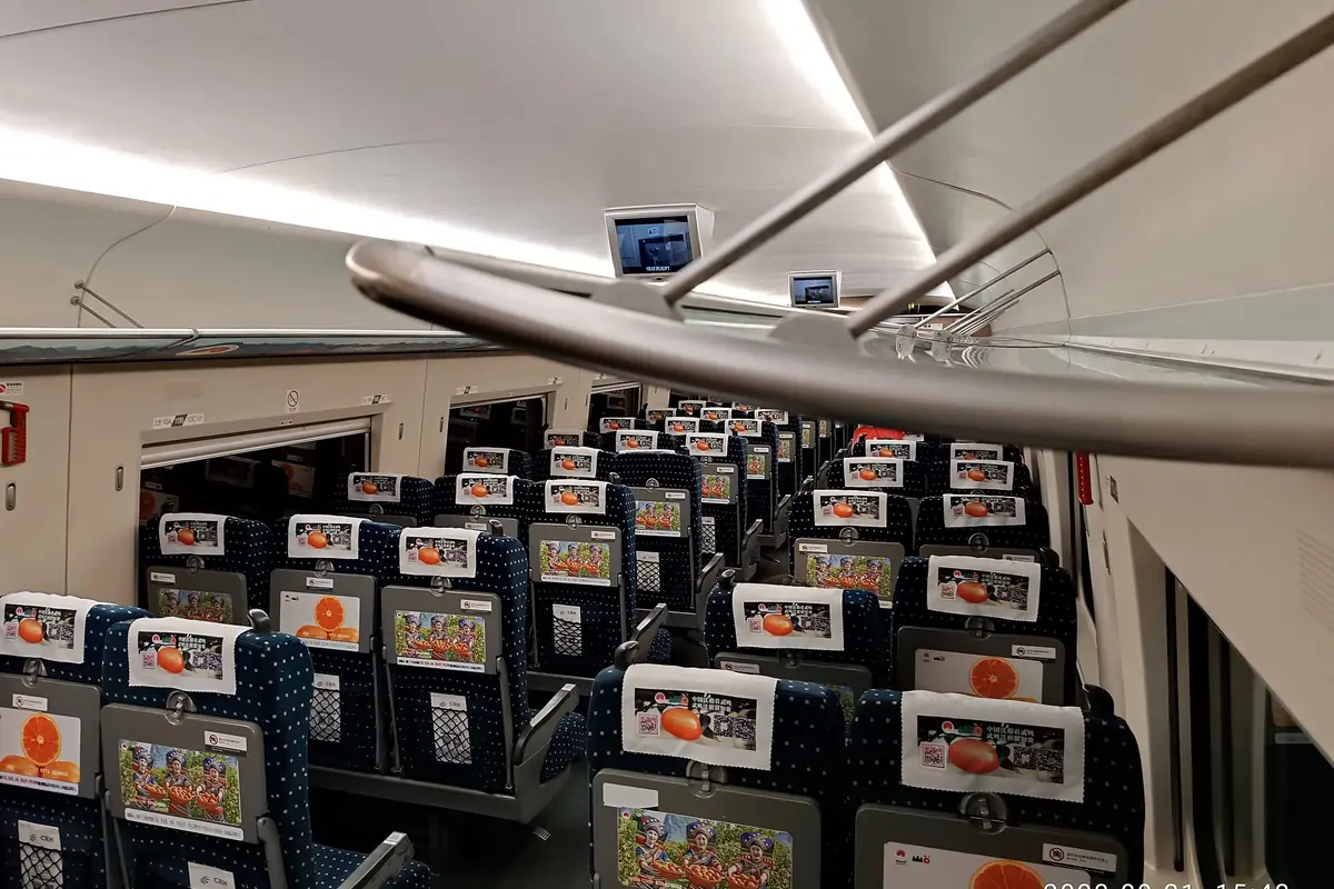 Train carriage with blue patterned seats and luggage stored overhead