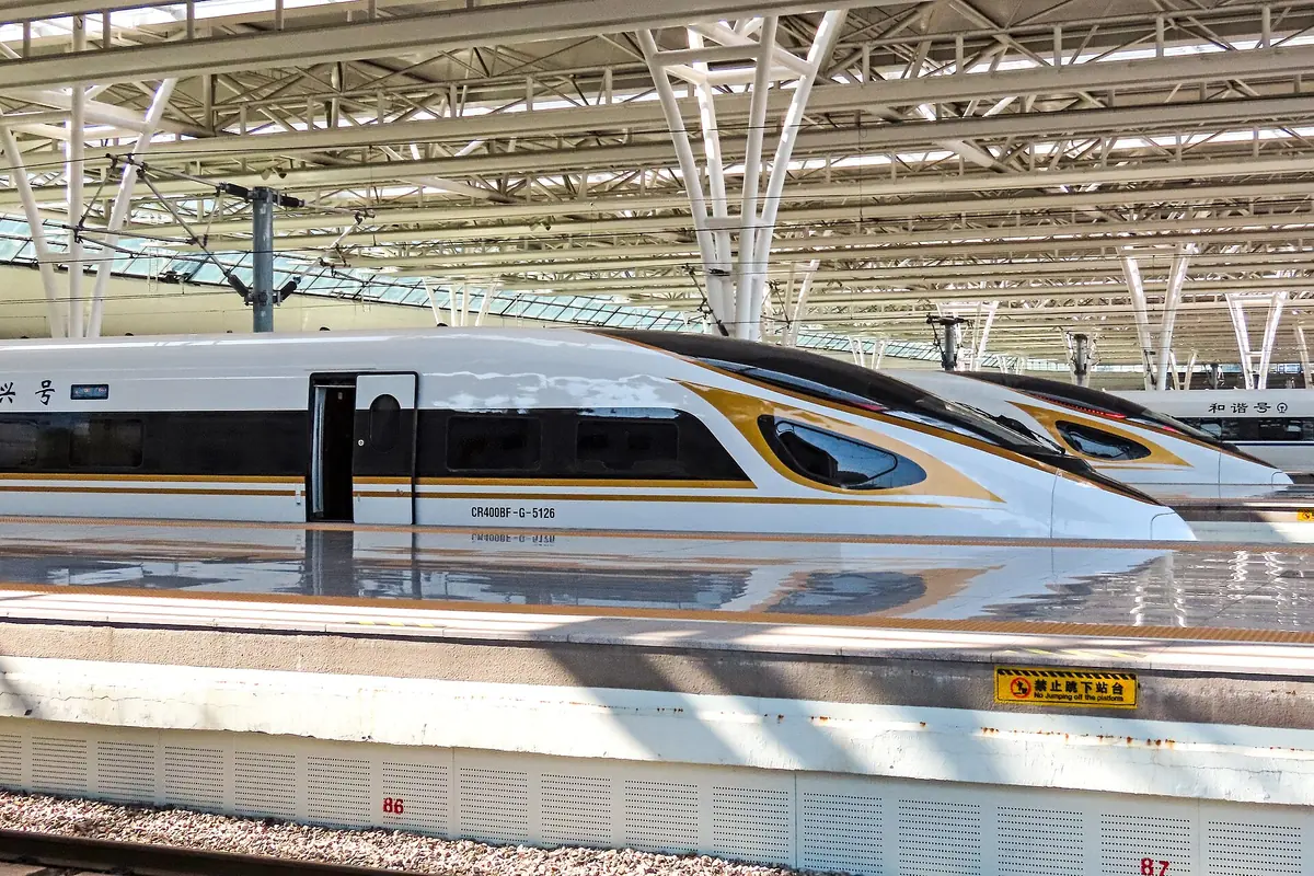 Streamlined high-speed train beside a platform under the steel roof of Shanghai Hongqiao Railway Station