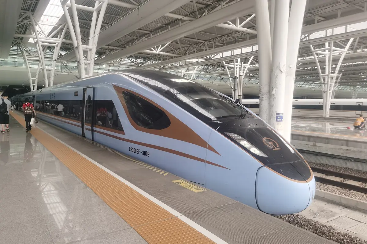 Train blanc à grande vitesse avec encadrement orange des fenêtres sous une marquise de gare