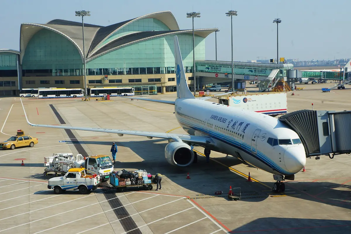 Passenger aircraft connected to a boarding bridge beneath green curved terminal roofs