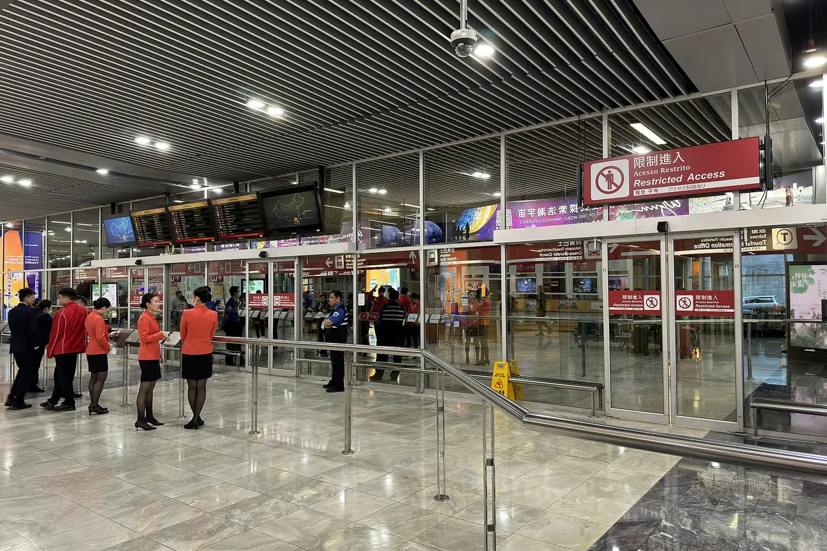 Viajeros haciendo cola en los mostradores del aeropuerto bajo señales y luces del techo