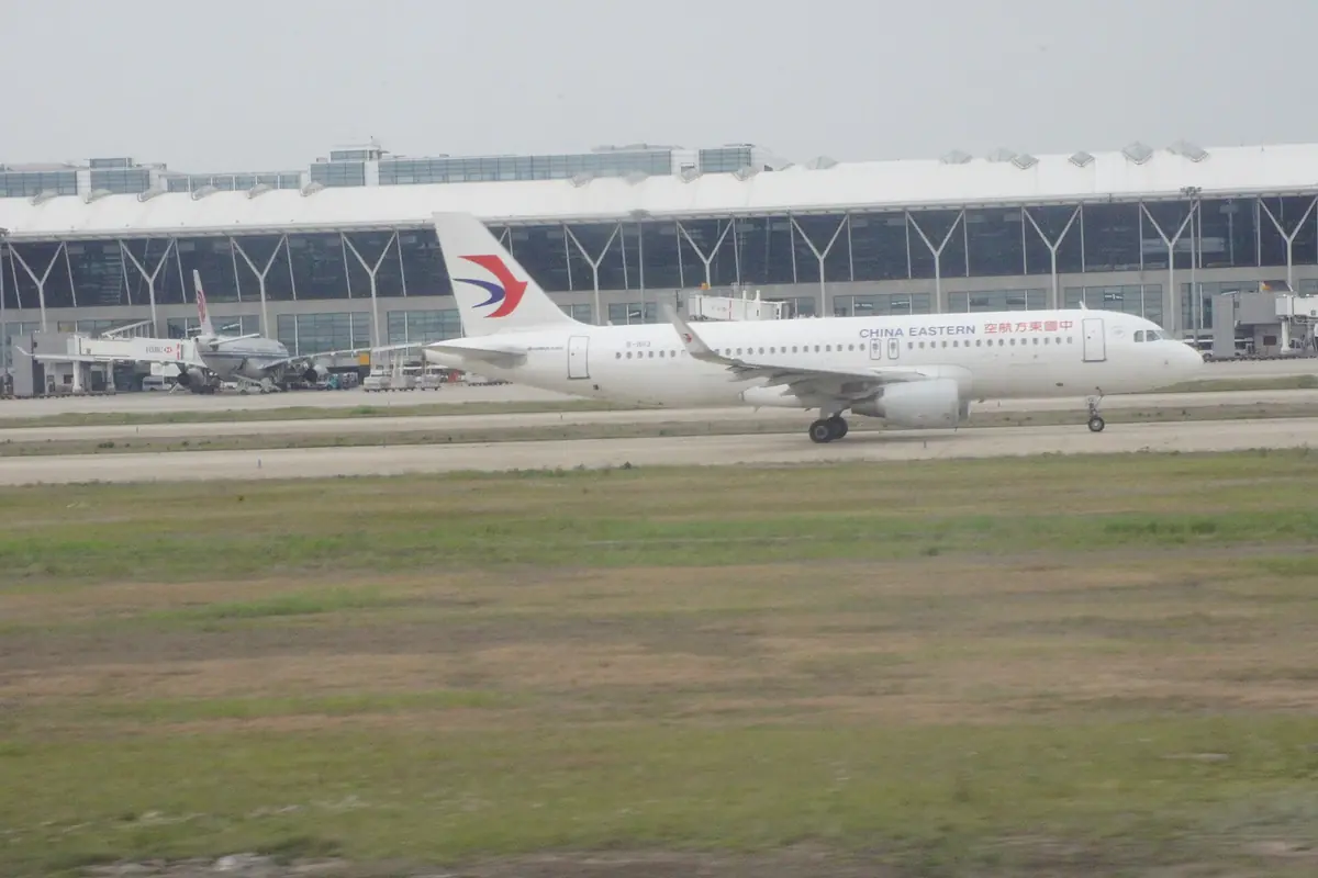 China Eastern passenger aircraft taxiing beside a glass airport terminal