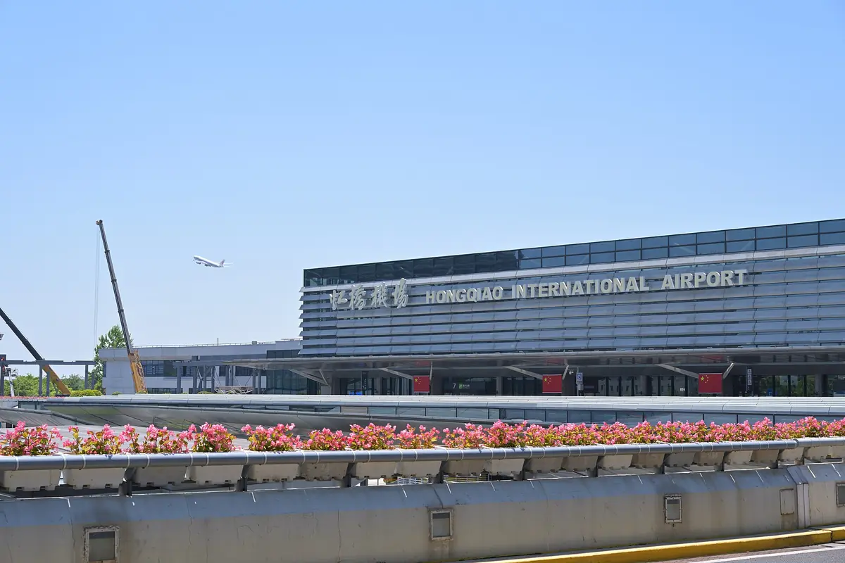 Shanghai Hongqiao International Airport terminal behind colorful roadside flowers