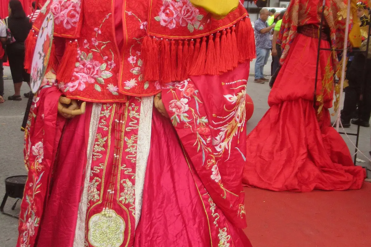 Close view of embroidered red ceremonial clothing with tassels and floral patterns