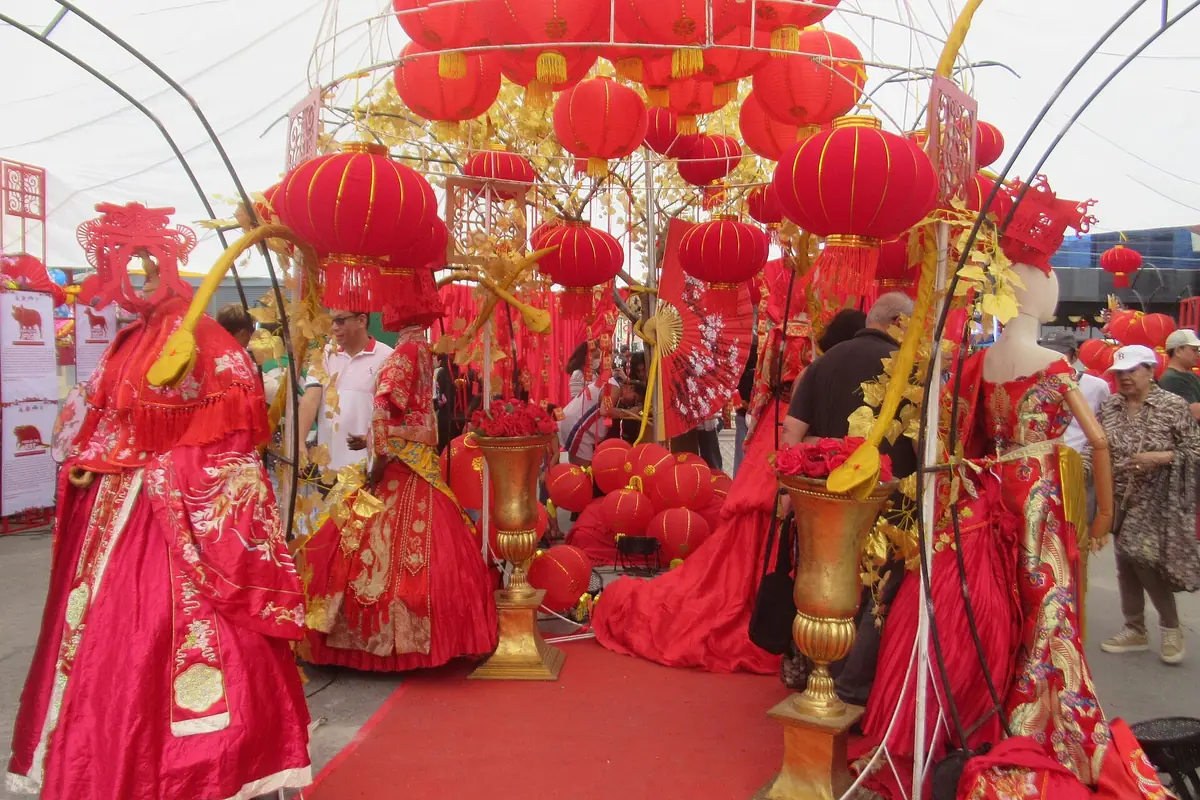 Performers in red-and-gold costumes beneath a canopy of red lanterns