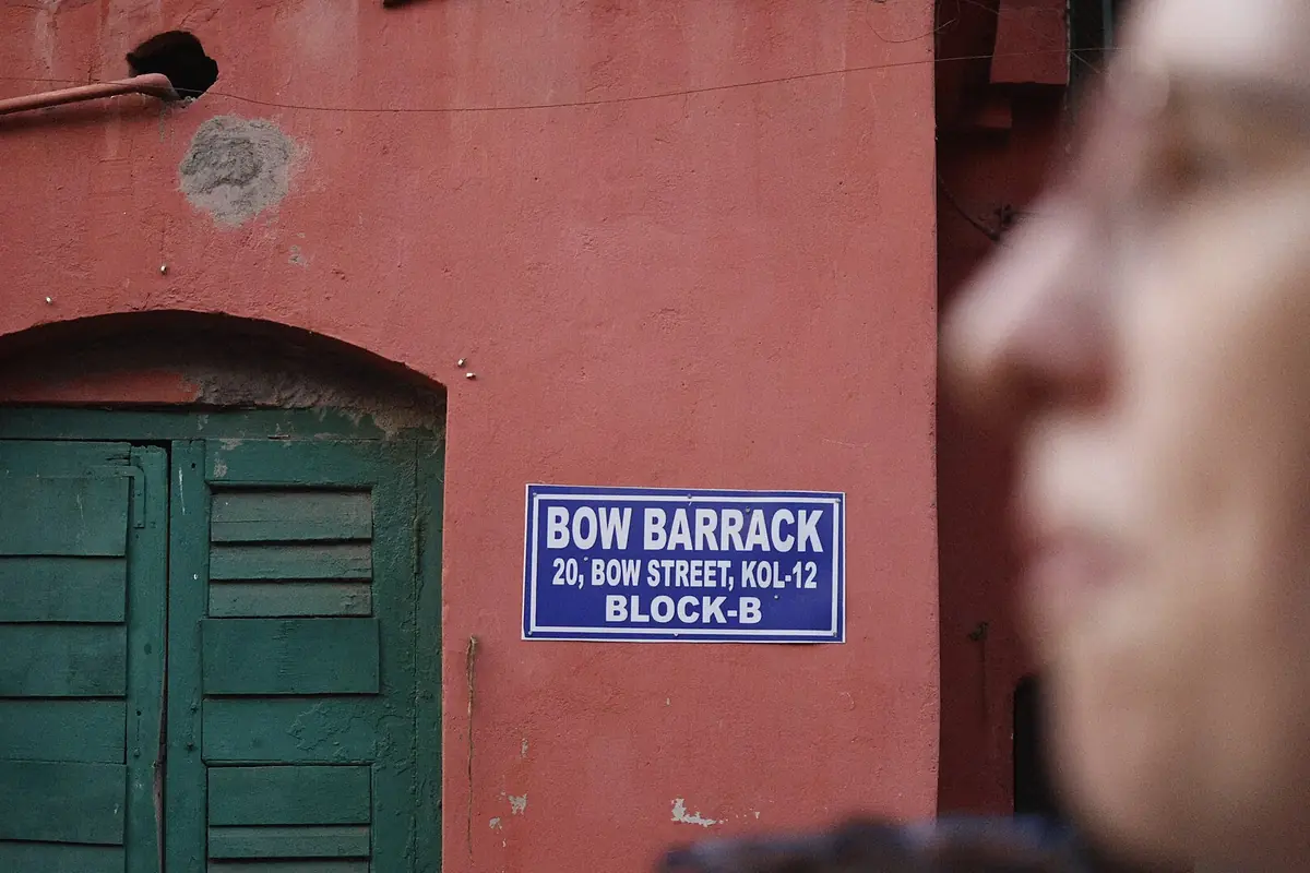 Green wooden door in a red wall beside a Bow Barrack street sign