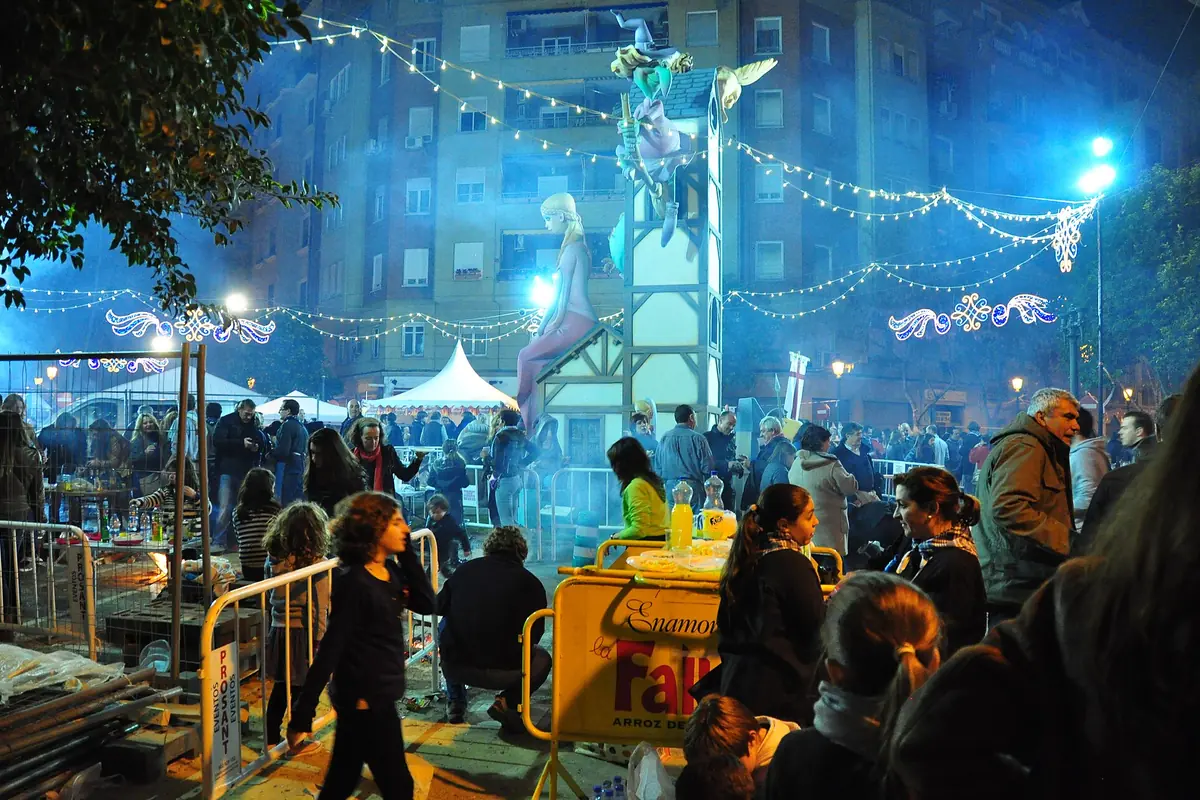 Crowded street celebration beneath blue-lit smoke and hanging decorative lights