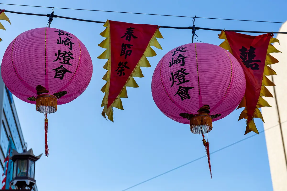 Pink lanterns with black Chinese characters hanging beside triangular festival banners