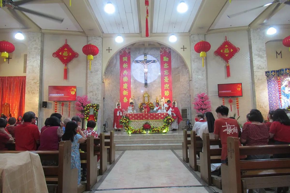 Worshippers in a church decorated with red lanterns and festive banners