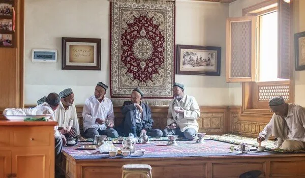 Group gathered around a tea table in a room with patterned wall textiles