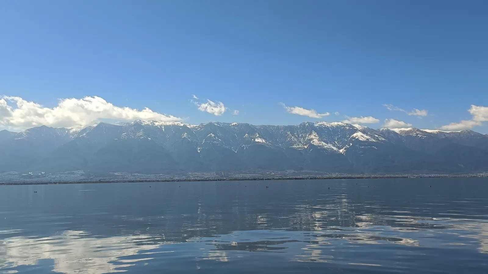 Calm Erhai Lake reflecting clouds below the Cangshan mountains in Dali, Yunnan