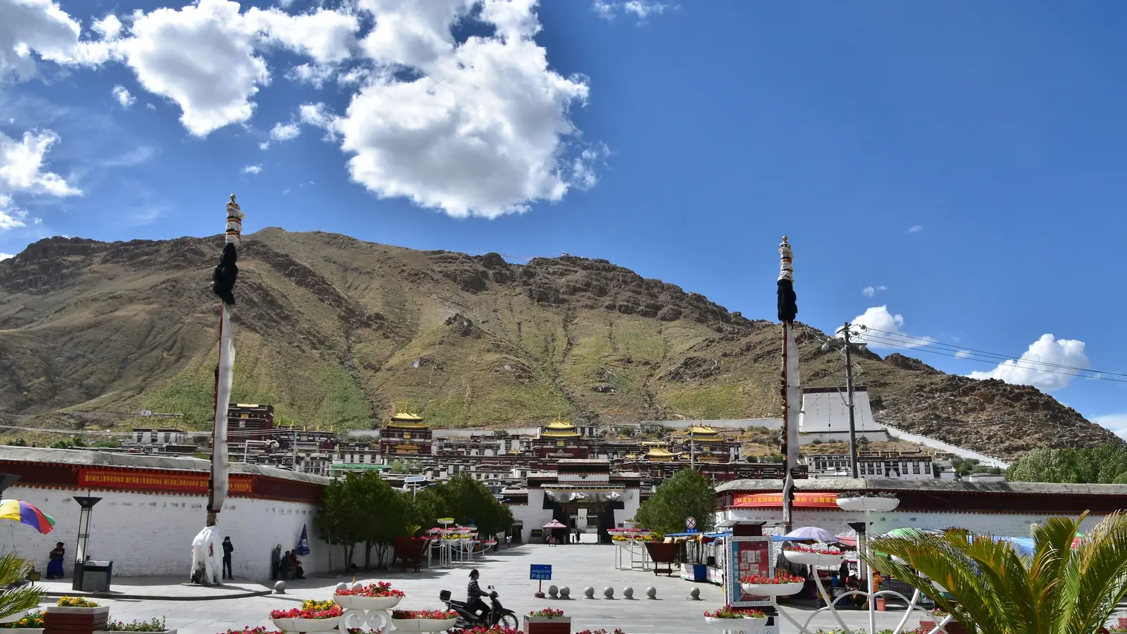 White-walled monastery complex beneath a bare mountain and blue sky in Shigatse