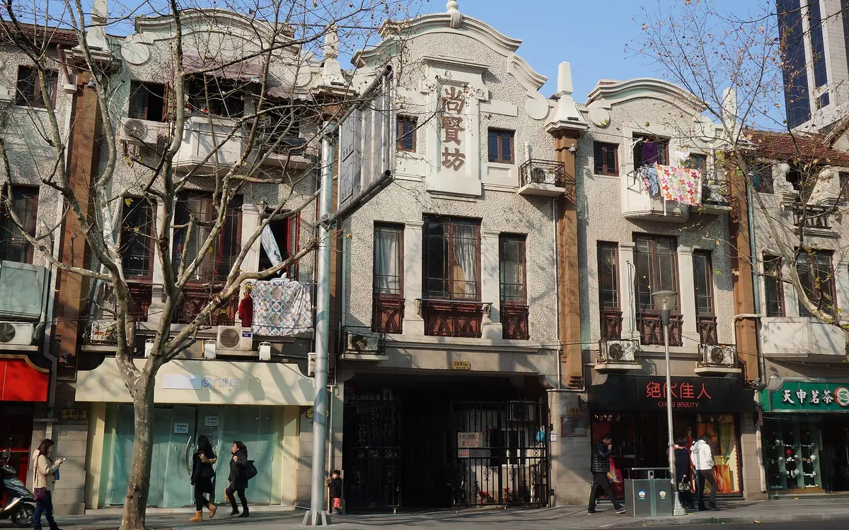 Weathered Shanghai shikumen buildings with ornate stone entrances beside a narrow street
