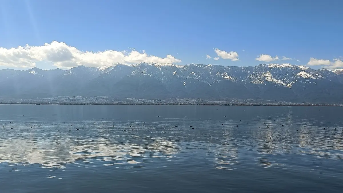 Snowy mountains reflected across a calm blue lake