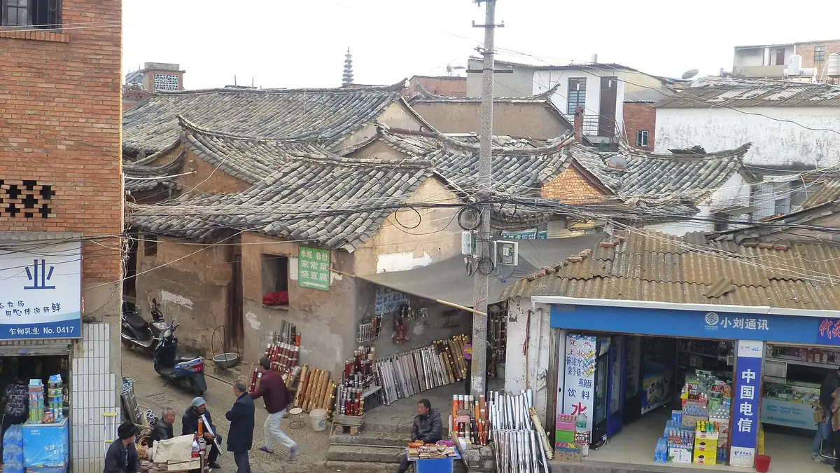 Calle de una aldea con casas de tejados de tejas, pequeños comercios y peatones
