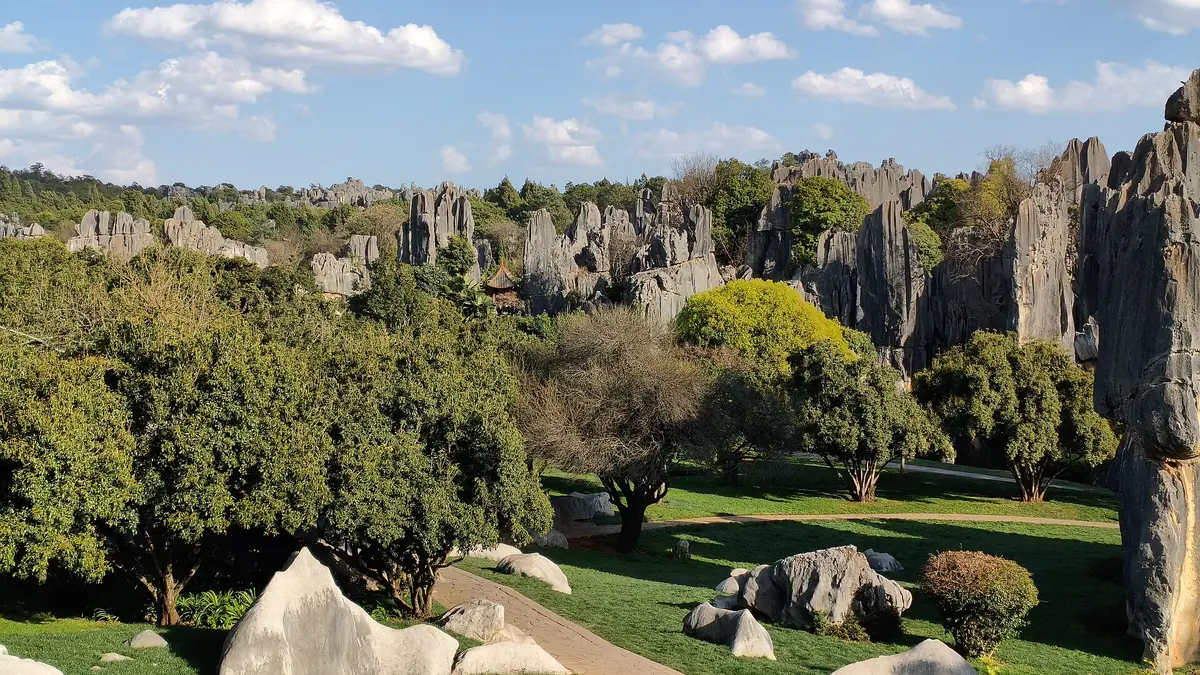 Vista aérea de pilares de piedra caliza que se elevan sobre césped cuidado y árboles en un parque ajardinado