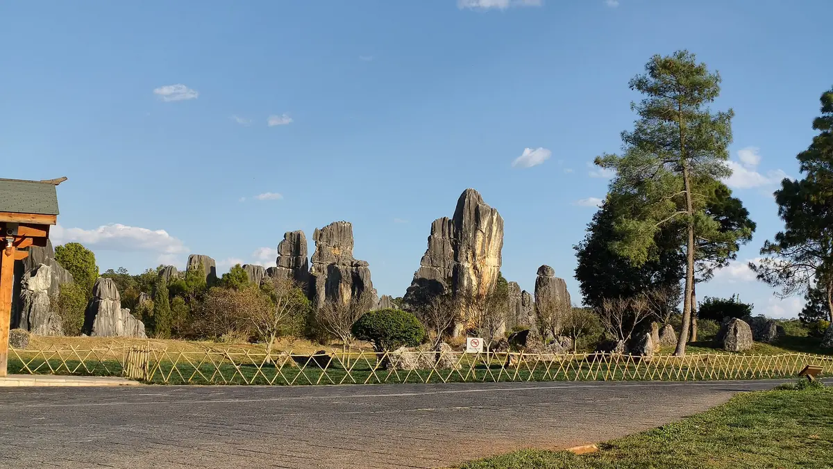 Tall limestone pillars and green planting beside a broad visitor walkway