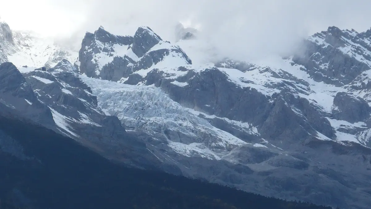 Snowy mountain ridges beneath thick white clouds