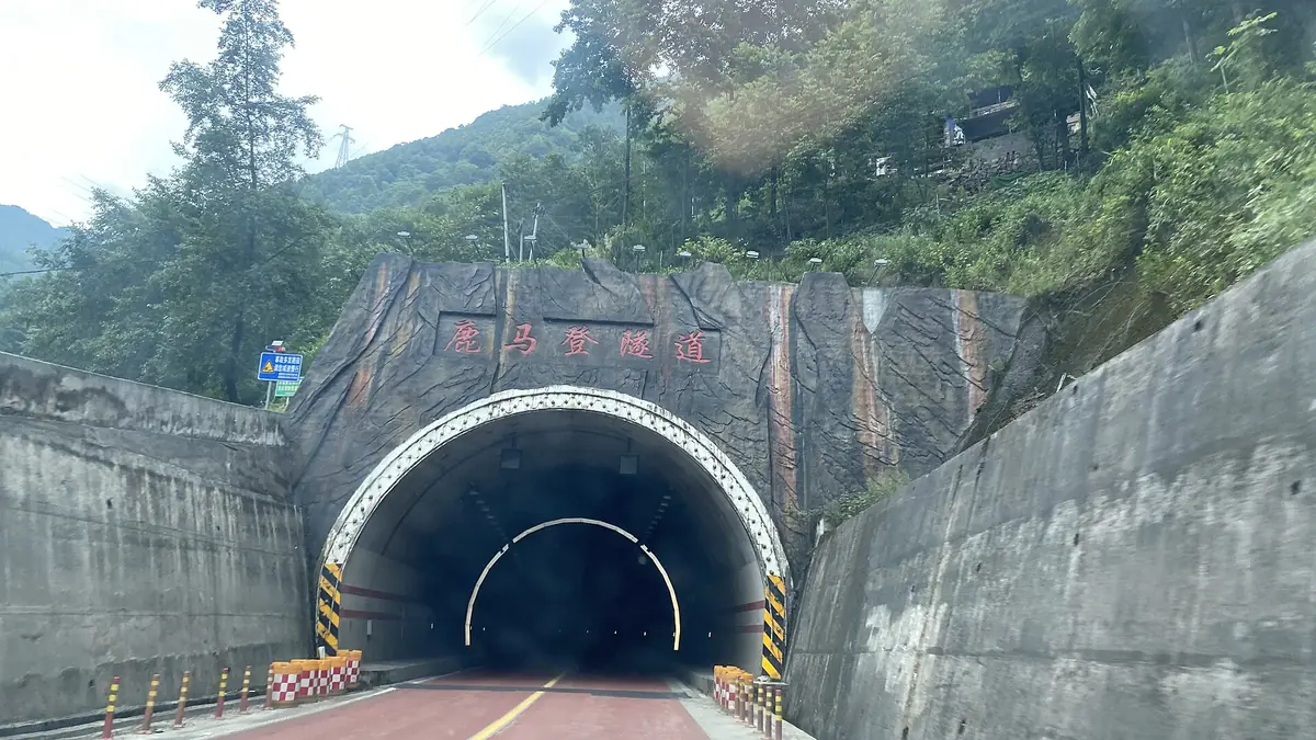 Jalan memasuki terowong bulat di bawah lereng bukit berbatu yang berhutan