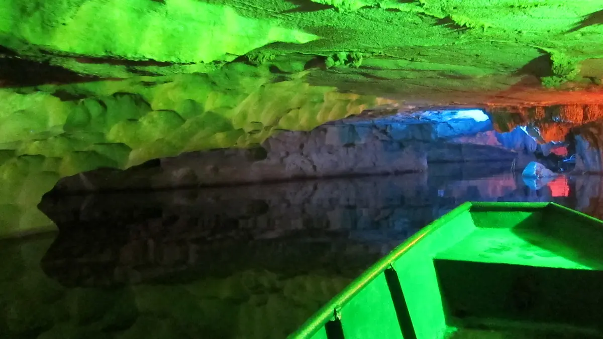 Pequeño bote dentro de una cueva iluminada con luces verdes y azules