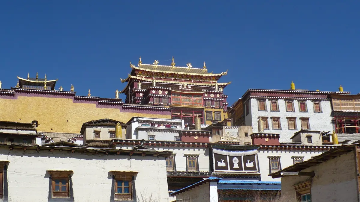 Tibetan monastery with white walls and golden roofs under a deep blue sky