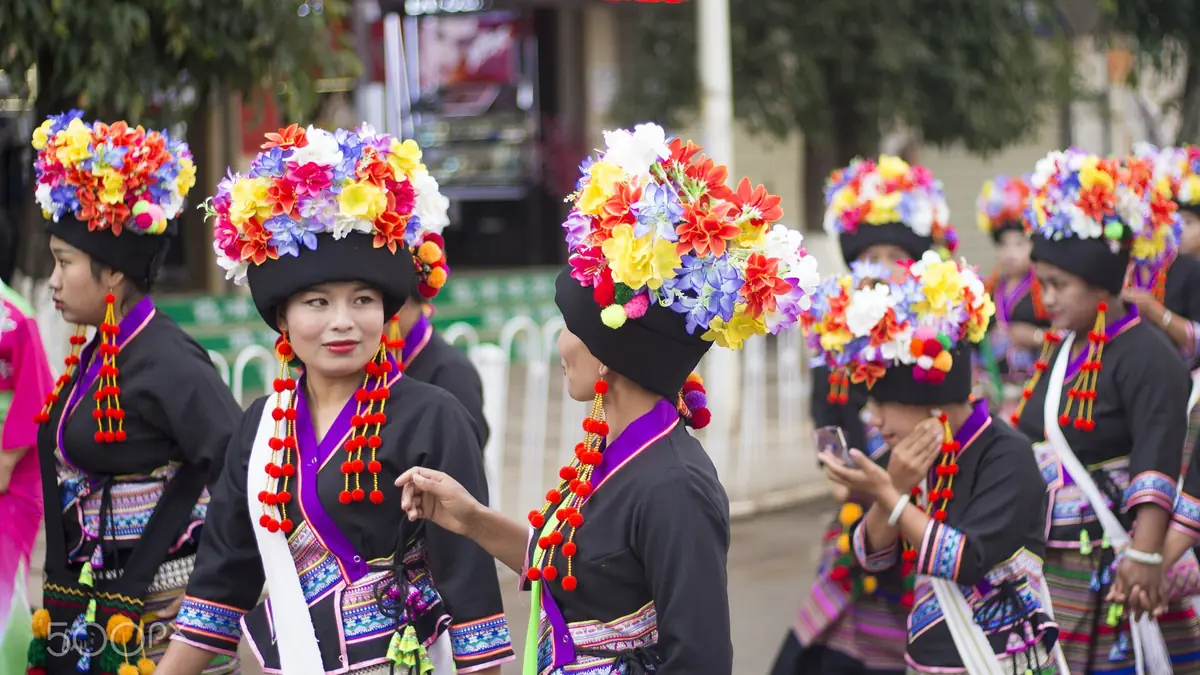 Women in traditional clothing wearing bright flower-covered headdresses