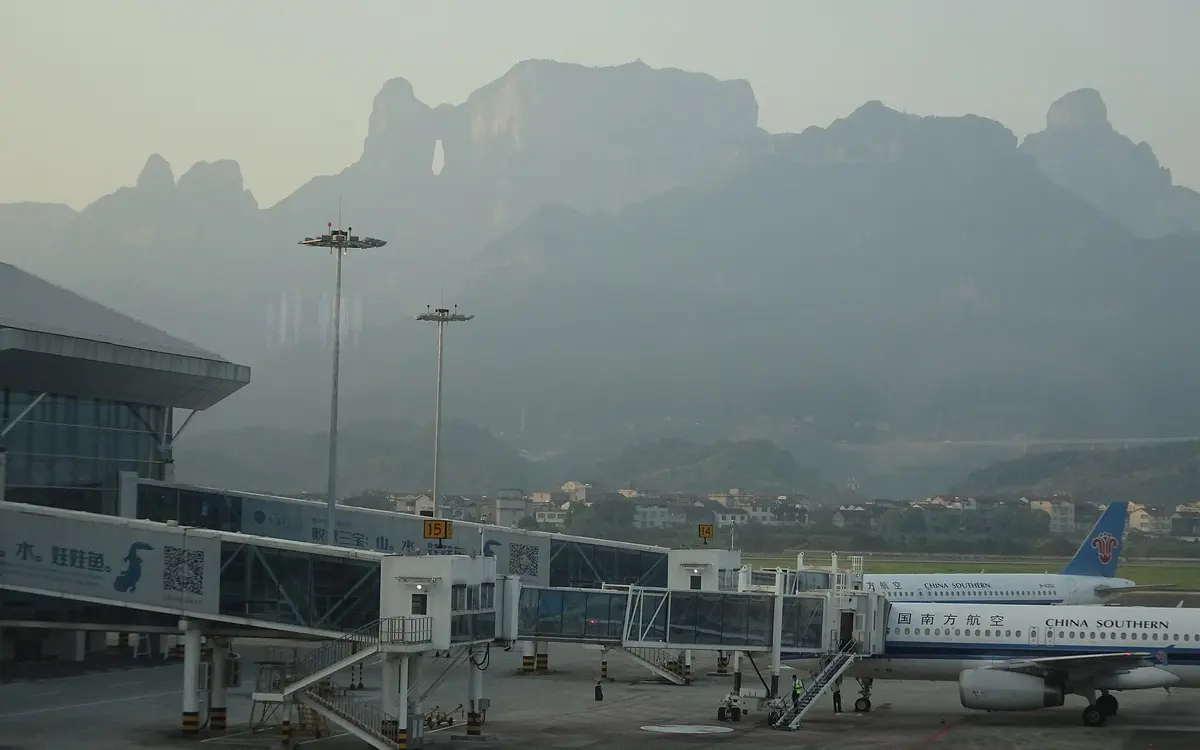 Zhangjiajie airport terminal and aircraft beneath hazy karst mountains