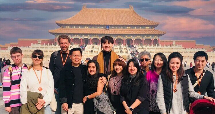 Group of travelers posing before a golden-roofed Forbidden City hall in Beijing