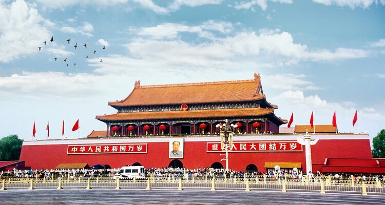 Red Tiananmen Gate and rows of flags against a bright sky in central Beijing